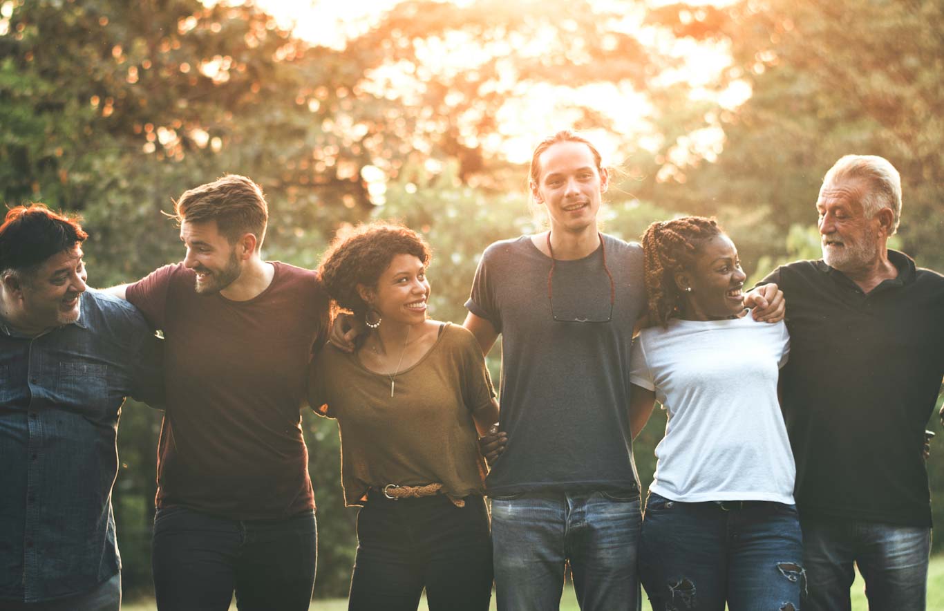 a group of people of various age and backgrounds standing in a line and smiling