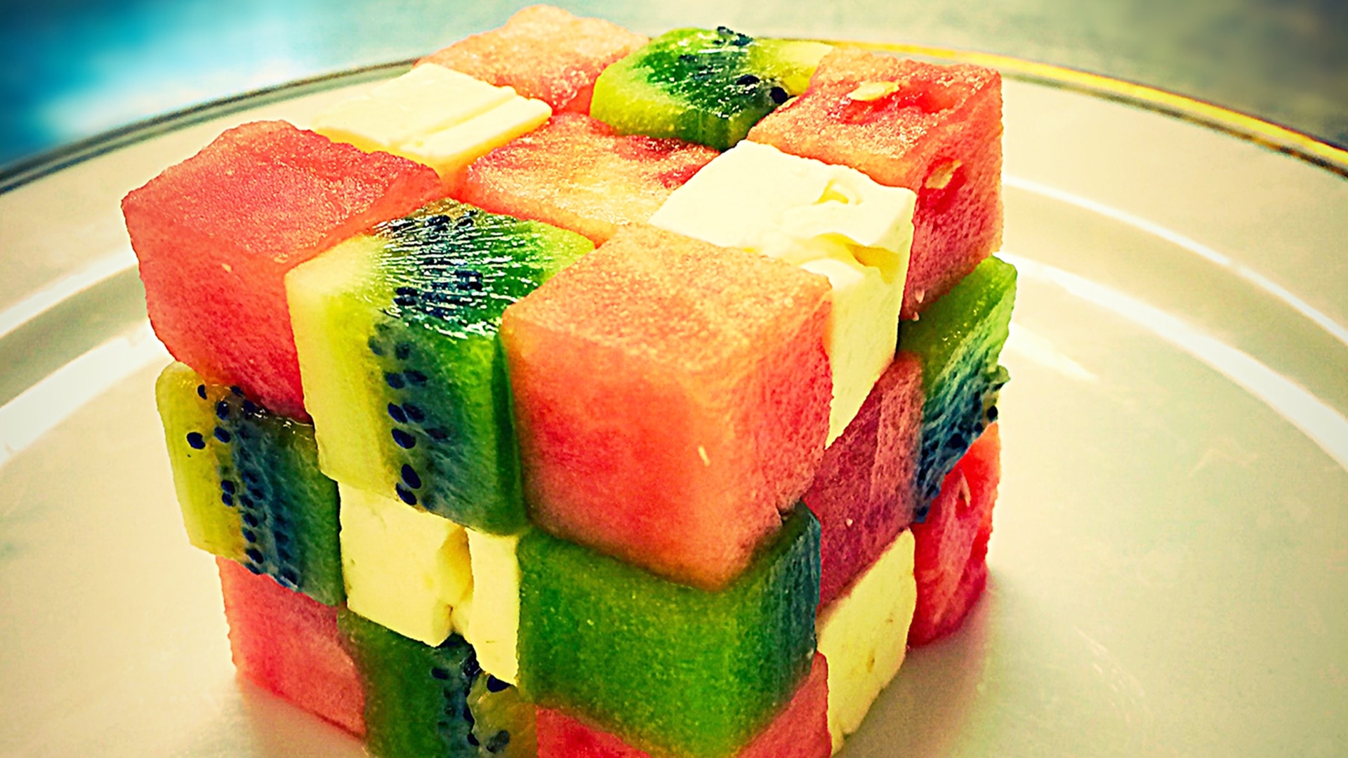 A cube composed of cubes of fruit on a plate