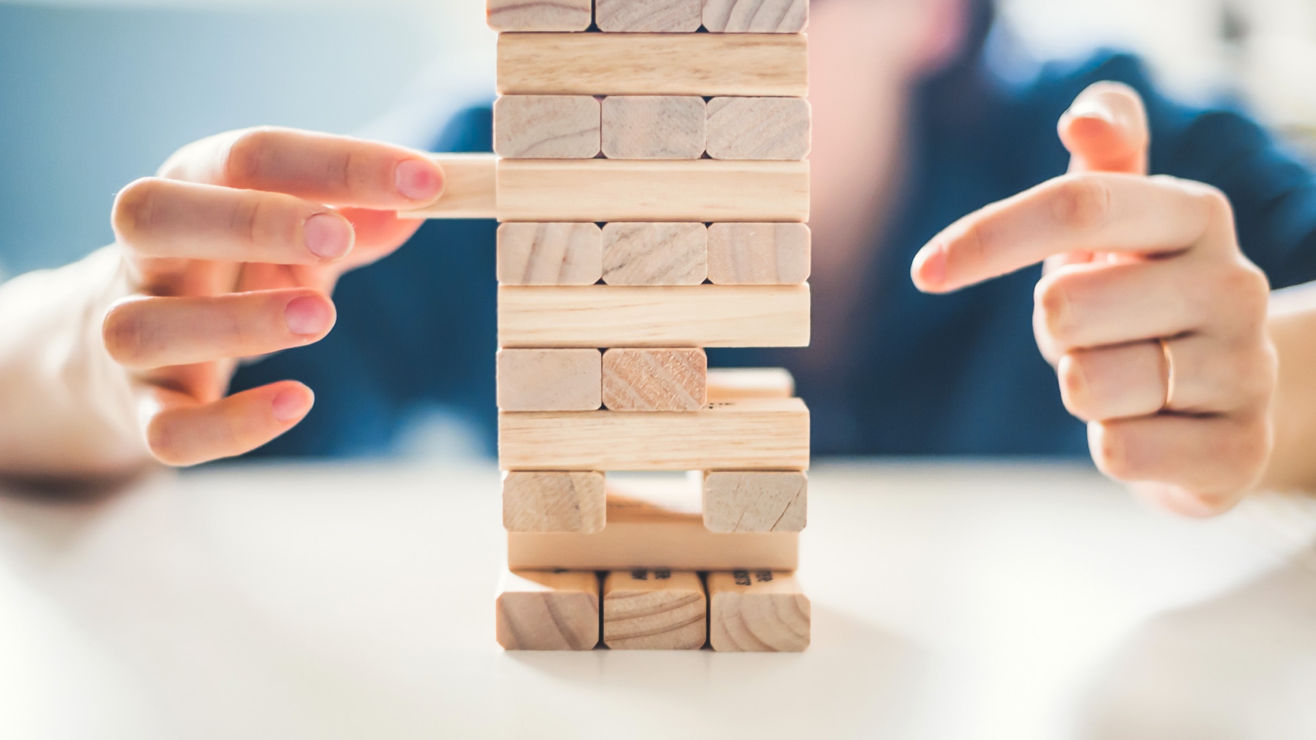    A person pulls out a piece from a Jenga tower