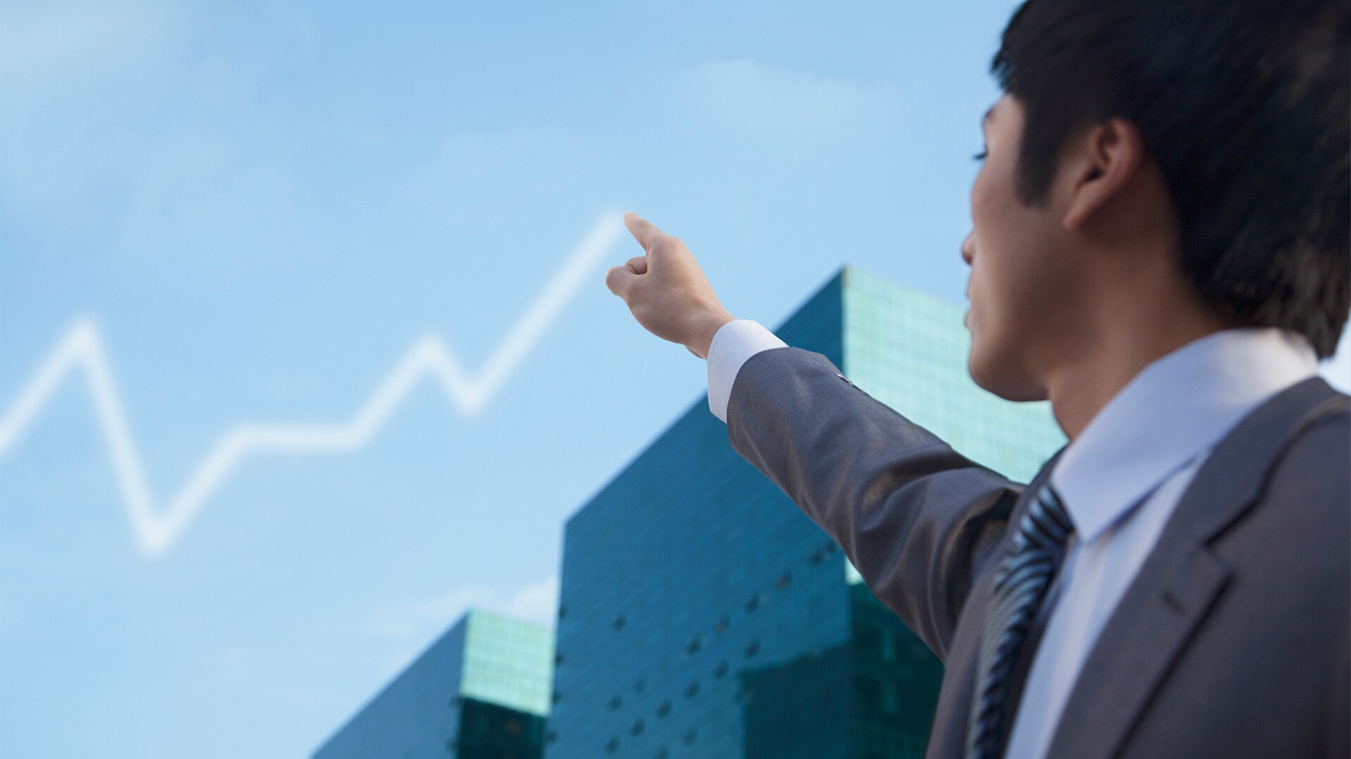     A man in a suit points at the sky where a graph can be seen 